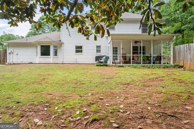 rear view of house with ceiling fan, a fenced backyard, a sunroom, a shingled roof, and a yard