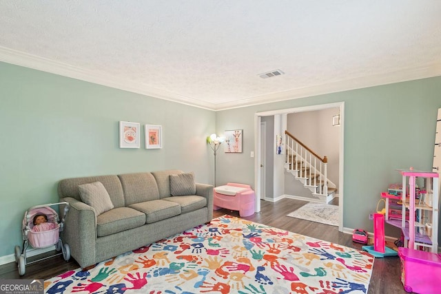 living room featuring visible vents, baseboards, wood finished floors, and stairway
