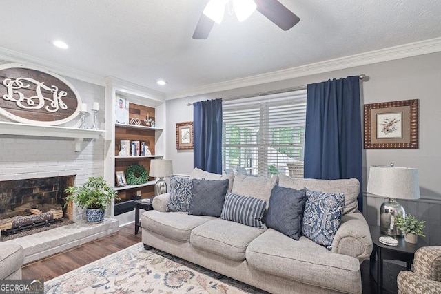 living area with crown molding, ceiling fan, a brick fireplace, and wood finished floors