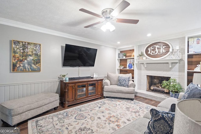 living area featuring crown molding, a ceiling fan, a brick fireplace, and wood finished floors