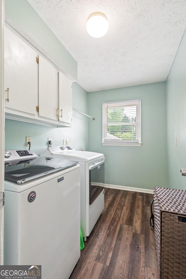 washroom featuring cabinet space, washing machine and clothes dryer, a textured ceiling, dark wood finished floors, and baseboards