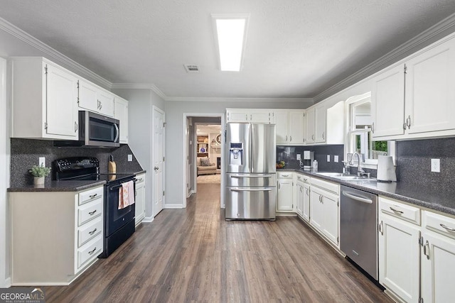kitchen with white cabinets, a sink, dark wood finished floors, stainless steel appliances, and backsplash