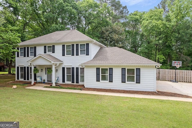 colonial-style house with roof with shingles, fence, and a front yard