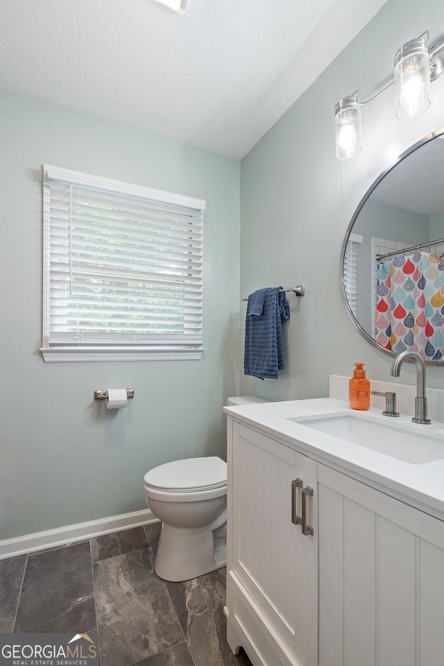 bathroom with vanity, baseboards, toilet, and a textured ceiling
