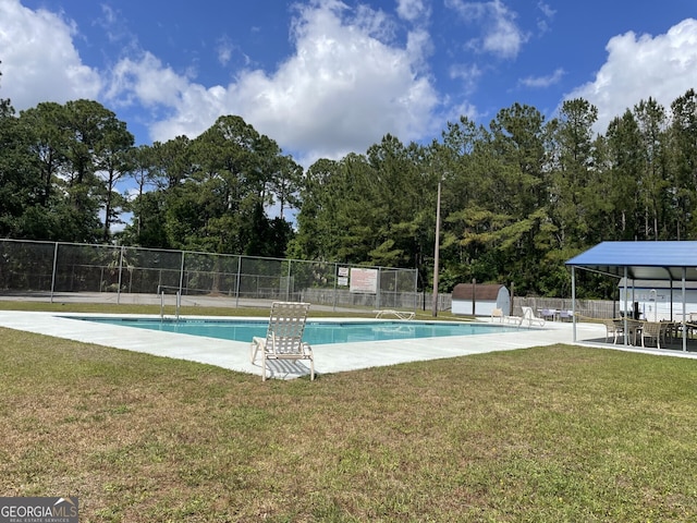 pool featuring a lawn, an outdoor structure, fence, and a shed
