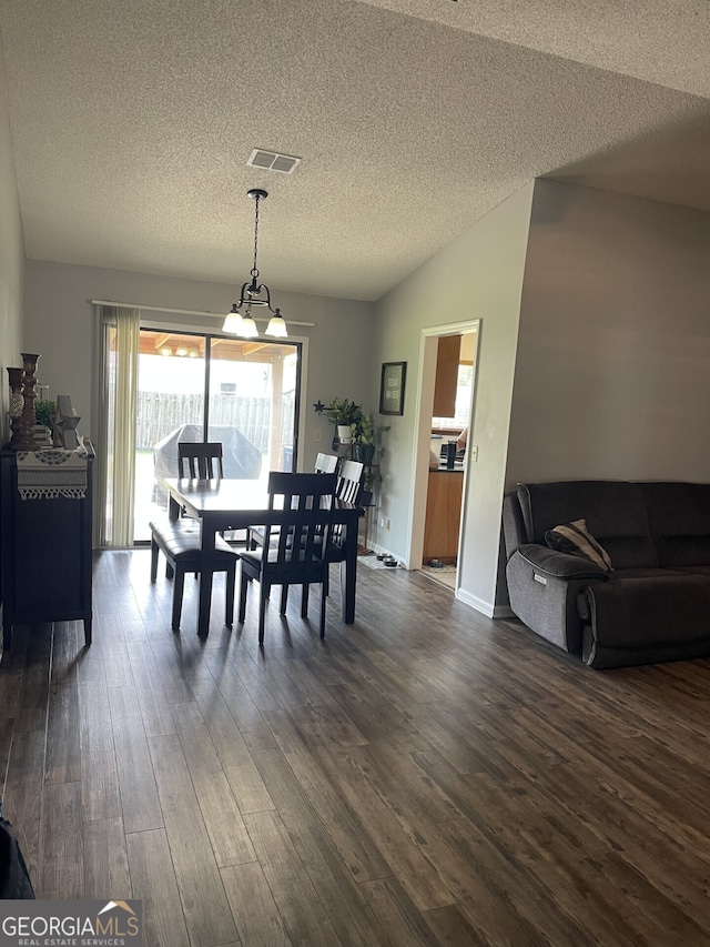 dining area featuring visible vents, a textured ceiling, and dark wood-type flooring