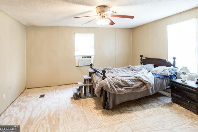bedroom with visible vents, a ceiling fan, a textured ceiling, and cooling unit