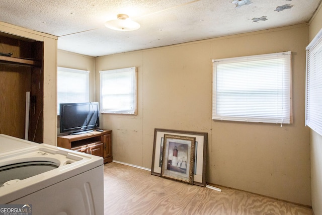 washroom featuring a textured ceiling, laundry area, and light wood-style floors