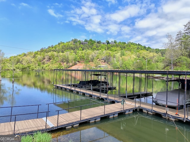 view of dock with a water view and a wooded view