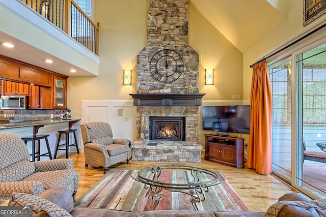 living room with light wood finished floors, a fireplace, and high vaulted ceiling