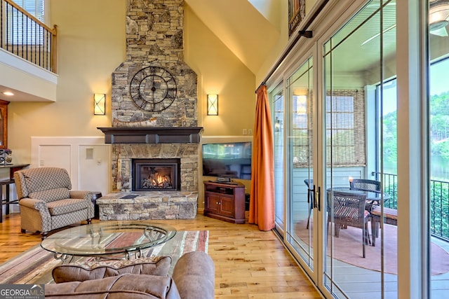 living area featuring a fireplace, french doors, wood finished floors, and a towering ceiling