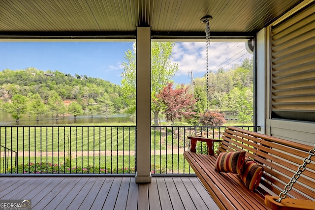 wooden terrace featuring a water view and a yard
