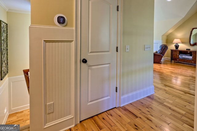 hall featuring crown molding, wainscoting, and light wood-type flooring