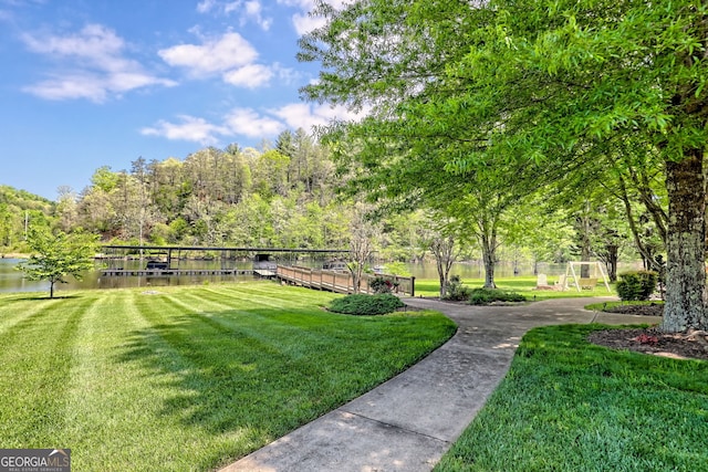 view of community featuring fence, a water view, and a yard
