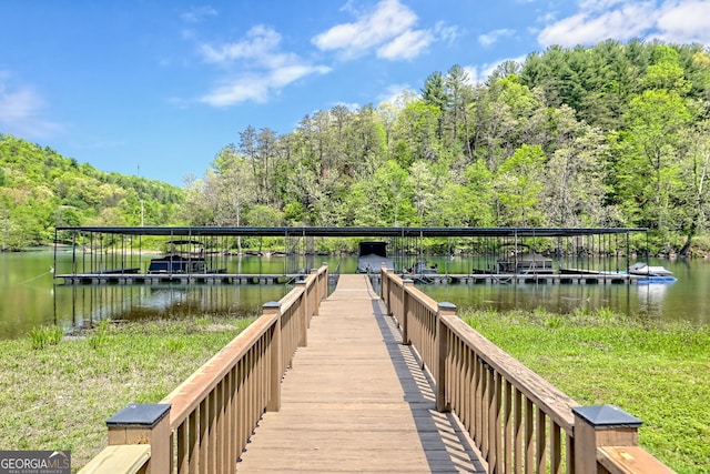 view of dock featuring a water view and a wooded view