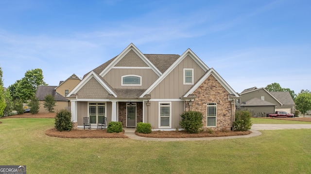 craftsman-style house with board and batten siding, stone siding, and a front lawn
