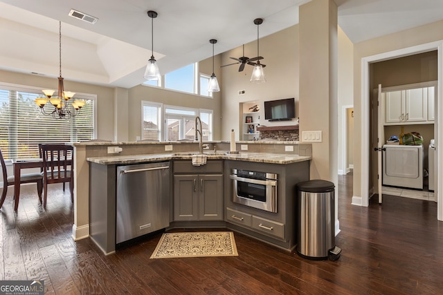 kitchen with visible vents, a sink, dark wood-style floors, stainless steel appliances, and washer and clothes dryer