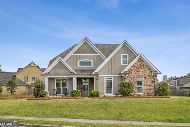 craftsman-style house featuring a porch, a shingled roof, board and batten siding, and a front yard