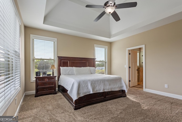 bedroom with a raised ceiling, baseboards, light carpet, and a ceiling fan