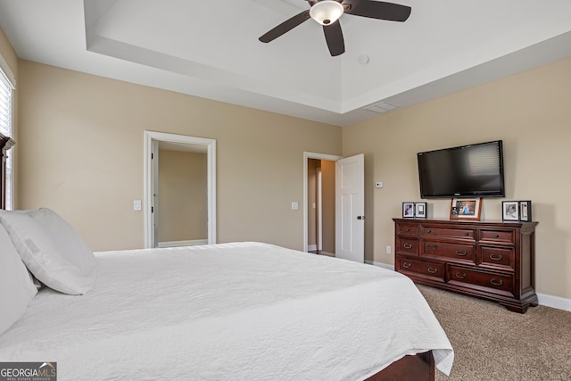 carpeted bedroom with a ceiling fan, baseboards, visible vents, and a raised ceiling