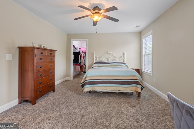 bedroom featuring visible vents, baseboards, a walk in closet, a ceiling fan, and carpet