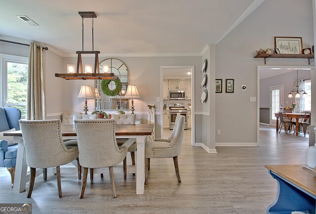 dining room with crown molding, a chandelier, visible vents, and light wood-style flooring
