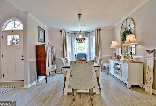dining space featuring light wood-type flooring, ornamental molding, and baseboards