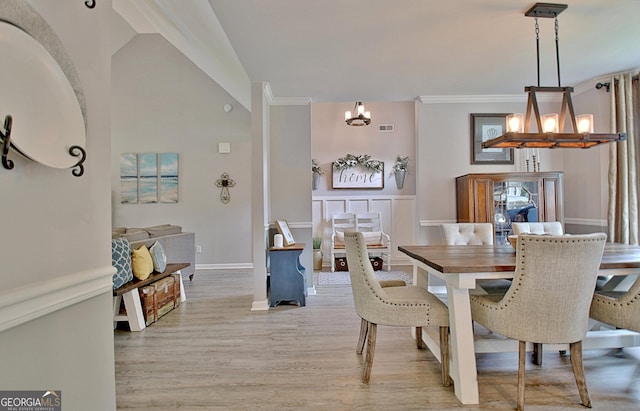 dining area with visible vents, baseboards, light wood finished floors, an inviting chandelier, and ornamental molding