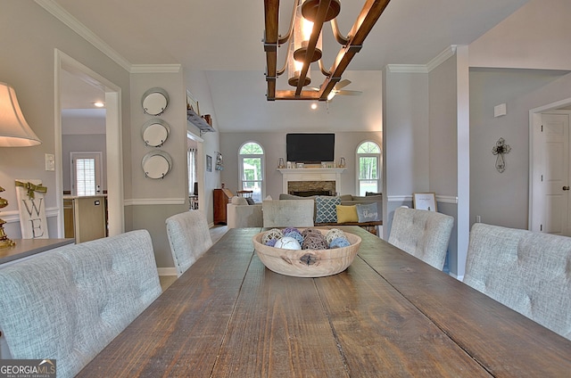 dining space featuring an inviting chandelier, lofted ceiling, and a fireplace