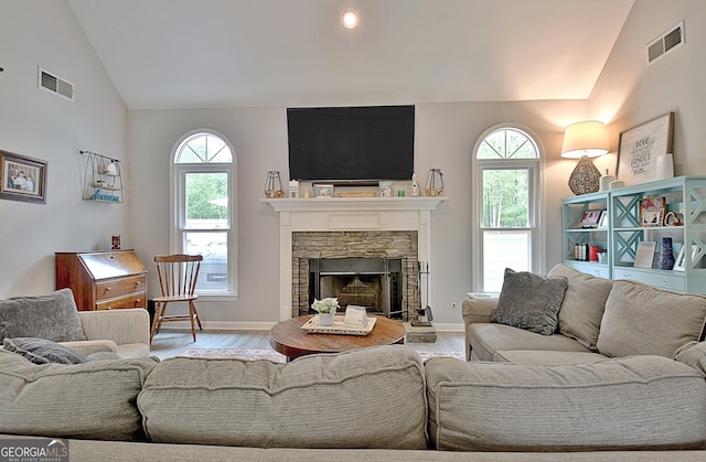 living room with visible vents, plenty of natural light, wood finished floors, and vaulted ceiling
