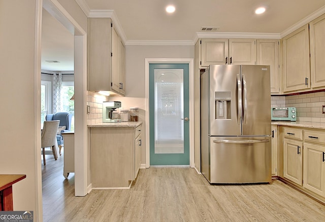 kitchen with visible vents, ornamental molding, light wood-style floors, stainless steel refrigerator with ice dispenser, and backsplash
