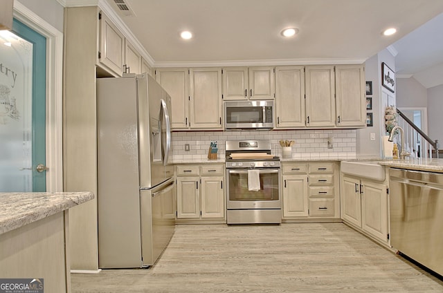 kitchen featuring light wood-type flooring, a sink, tasteful backsplash, and stainless steel appliances