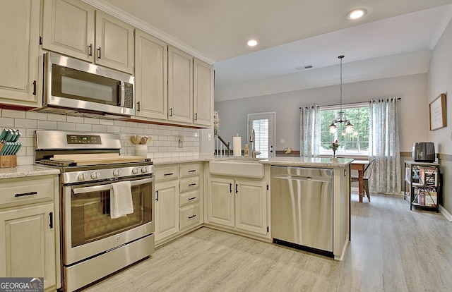kitchen with a sink, light wood-style floors, stainless steel appliances, and a peninsula