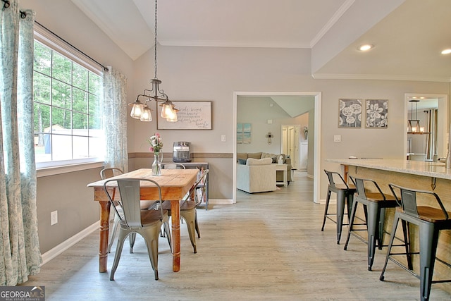 dining area featuring light wood-type flooring, ornamental molding, and a chandelier