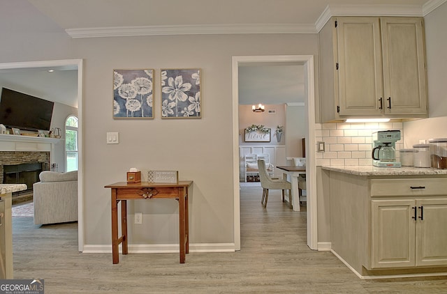 hallway with baseboards, ornamental molding, and light wood finished floors