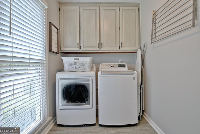 laundry room with washer and dryer, baseboards, cabinet space, and light wood-type flooring