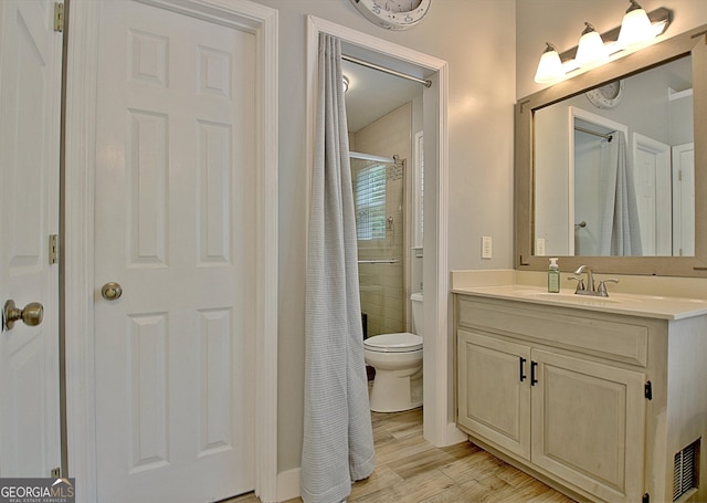 bathroom with vanity, a shower with shower curtain, wood finished floors, and toilet