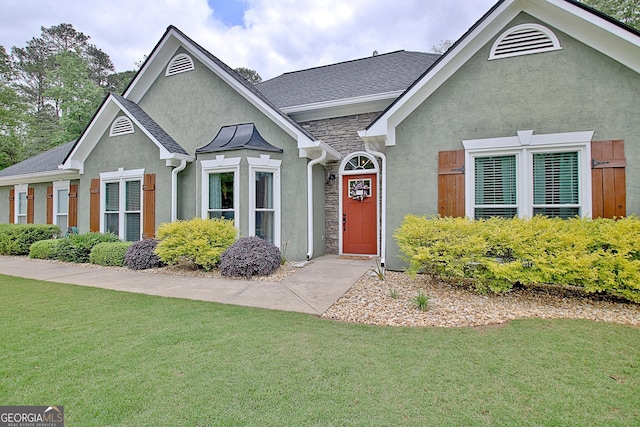 view of front of home featuring a front yard, stone siding, and stucco siding