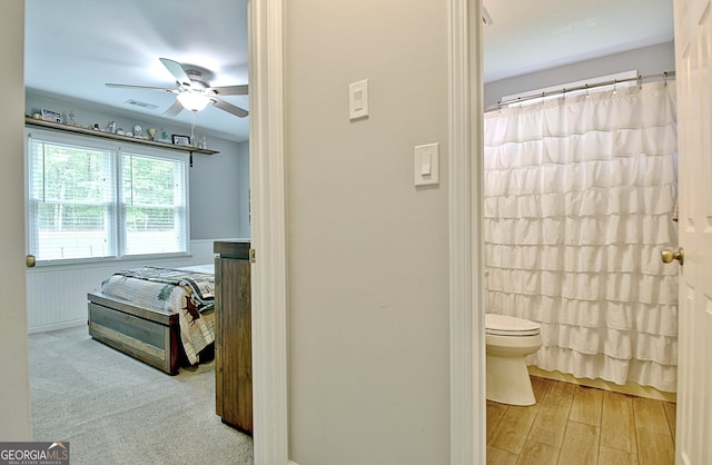 bathroom featuring a ceiling fan, toilet, visible vents, and a shower with curtain