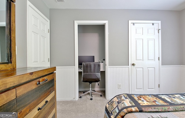 bedroom with a wainscoted wall, visible vents, and light colored carpet
