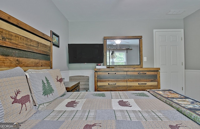 bedroom featuring a wainscoted wall and visible vents
