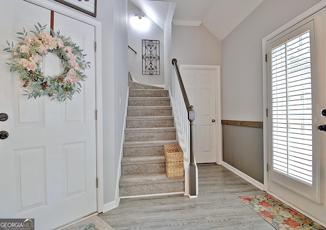 foyer featuring a wealth of natural light, light wood-type flooring, stairs, and lofted ceiling