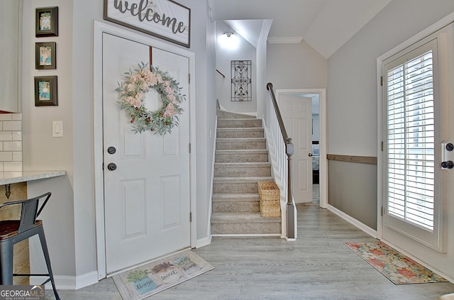 foyer entrance with baseboards, stairs, wood finished floors, and vaulted ceiling