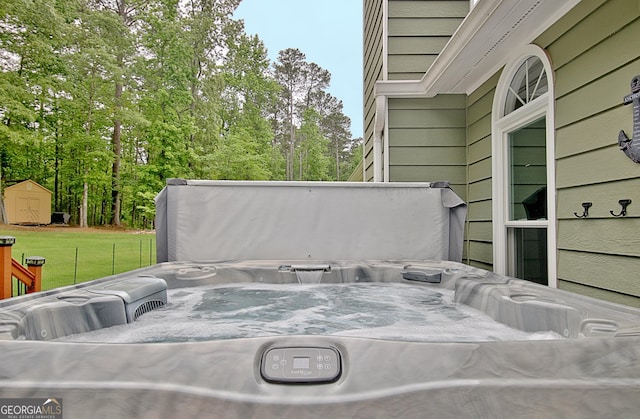 view of patio / terrace featuring outdoor lounge area, a hot tub, a shed, and an outbuilding
