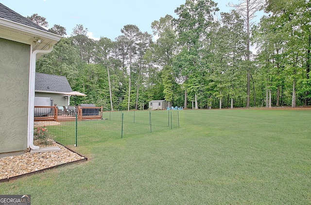 view of yard with fence, an outdoor structure, a deck, and a storage shed