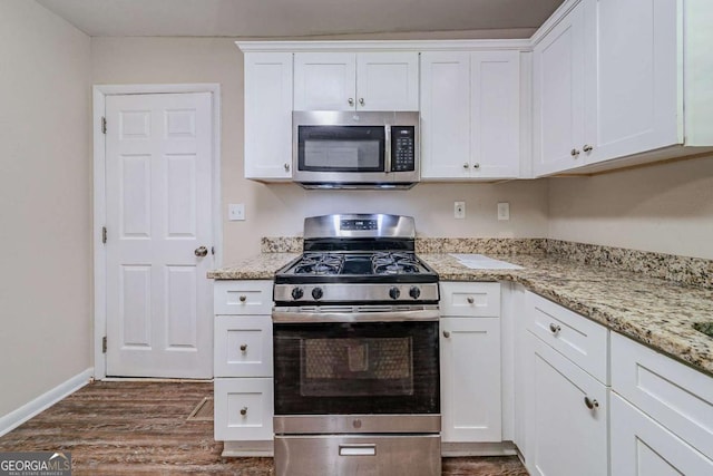 3497 Glensford Dr, Decatur, GA 30032 - kitchen with appliances with stainless steel finishes, light stone counters, dark wood finished floors, and white cabinetry