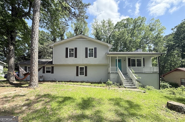 tri-level home with a porch, a chimney, and a front yard