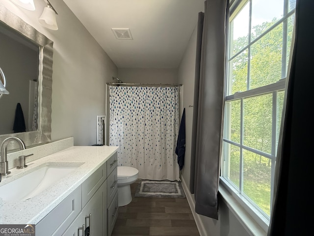 bathroom featuring plenty of natural light, toilet, wood finished floors, and visible vents