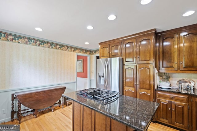 681 Hampton Pl SW, Marietta, GA 30064 - kitchen with light wood-style floors, stovetop with downdraft, a center island, stainless steel fridge, and dark stone counters