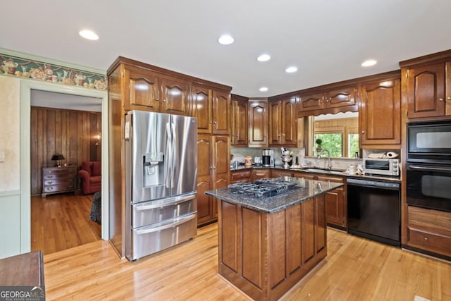 681 Hampton Pl SW, Marietta, GA 30064 - kitchen with a center island, dark stone counters, a sink, light wood-style flooring, and black appliances